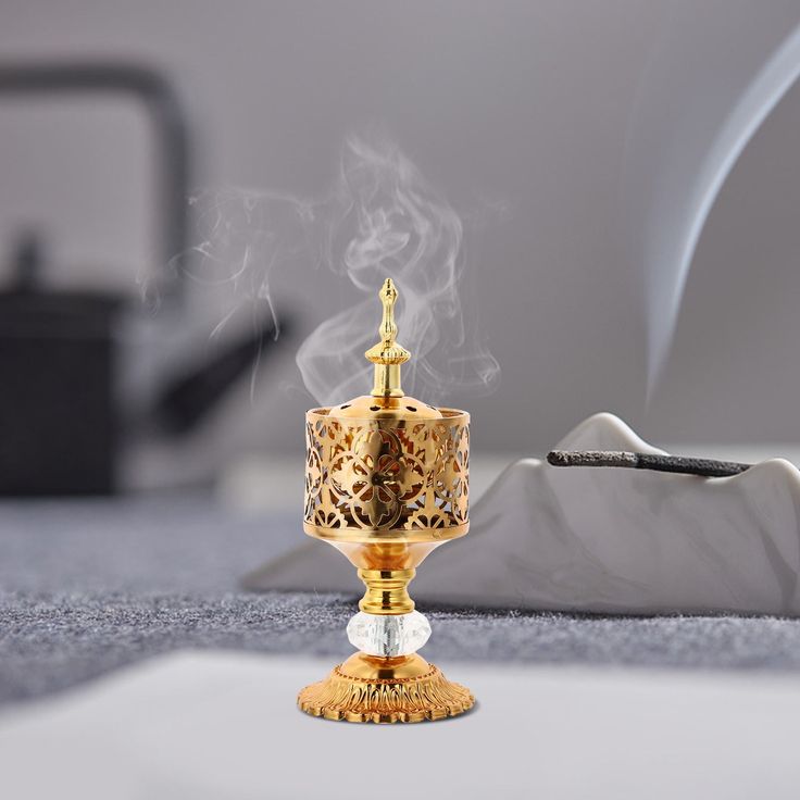 Decorative gold incense burner with smoke on a gray surface