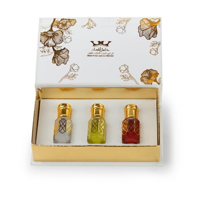 Three small bottles of perfume in a decorative box with floral patterns and a brand logo.